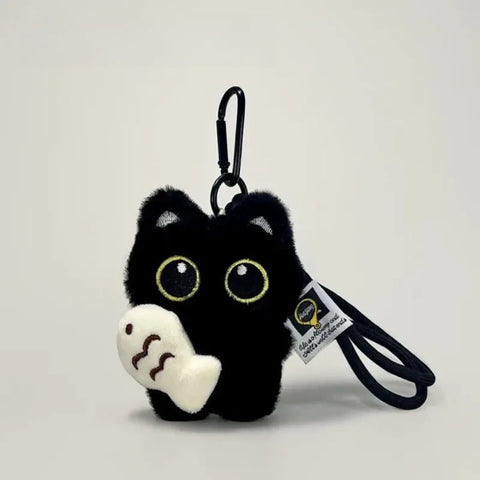 Black plush cat keychain holding a white fish, with clip and wrist strap
