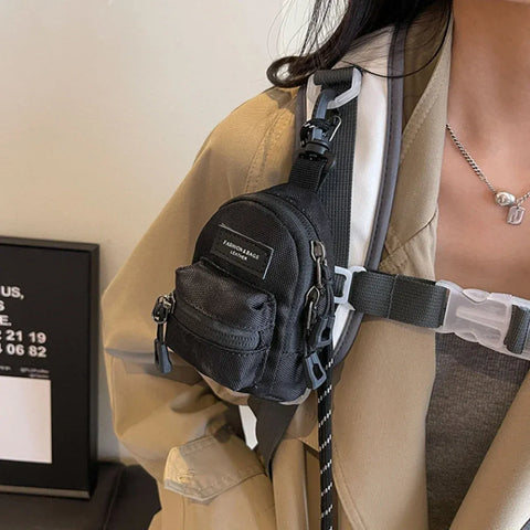 Black mini crossbody bag worn across the chest with front zip pocket